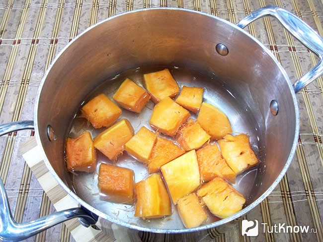 Очищенная тыква нарезанная кубиками находится в кастрюле с водой