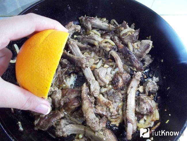 Из апельсина выдавливается сок в сковороду к мясу