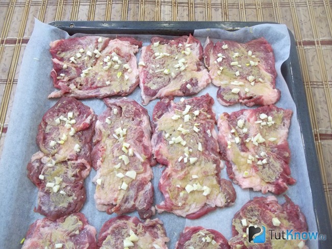 Мясо смазано горчицей и выложен чеснок