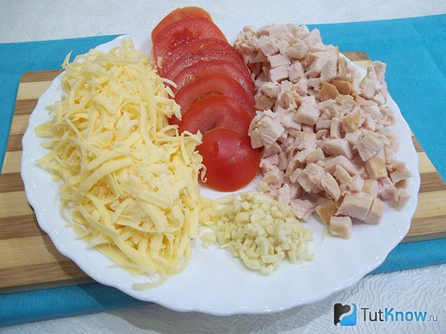 Помидоры, мясо и чеснок нарезаны кусочками, а сыр натерт на терке