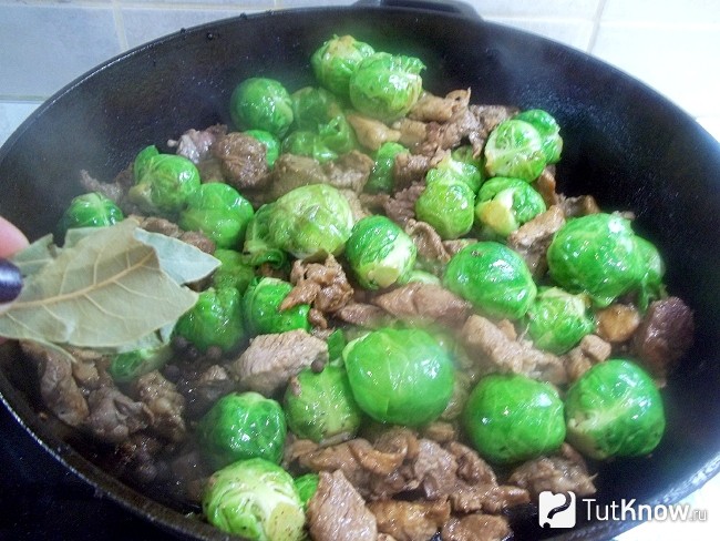 Мясо жарится в сковороде с капустой и добавлены пряности