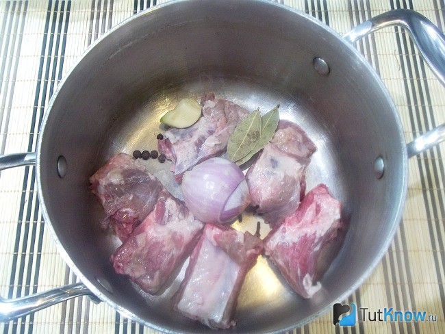 Мясо нарезано кусочками и опущено в кастрюлю для варки с луковицей и пряностями