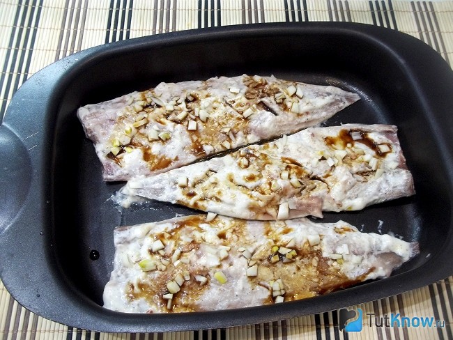 Маринованная скумбрия выложена на противень для запекания и полита соевым соусом