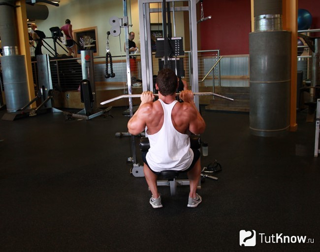 Атлет выполняет тягу Т-грифа узким хватом