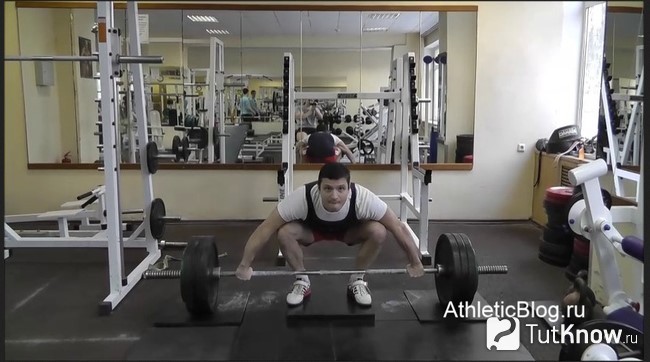 Спортсмен выполняет тягу штанги из ямы