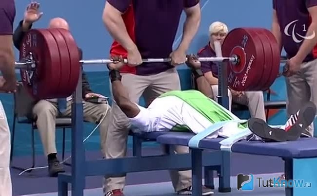 Атлет выполняет жим штанги лёжа на турнире