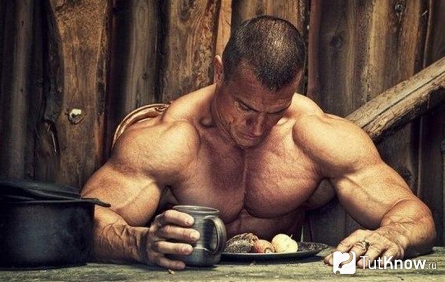 Спортсмен сидит за столом с едой
