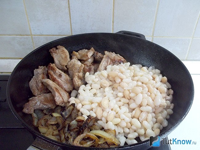 Жареный лук с мясо и отварная фасоль соединены в сковороде