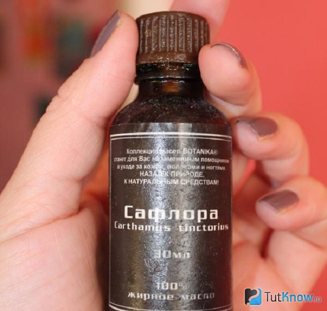 Бутылочка сафлорового масла в руке