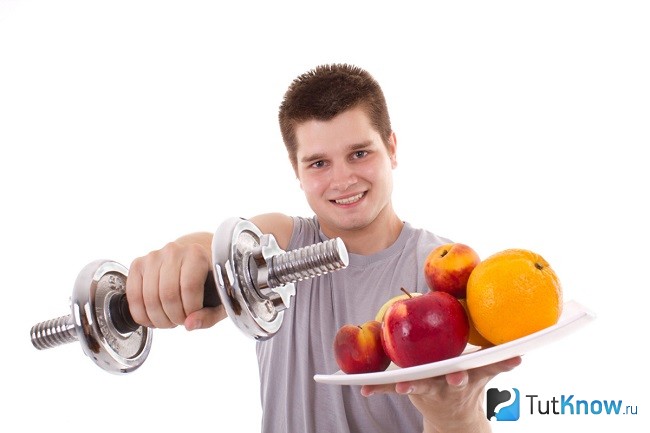 Парень с гантелей и фруктами
