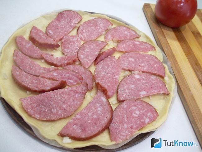 На тесто выложена нарезанная колбаса