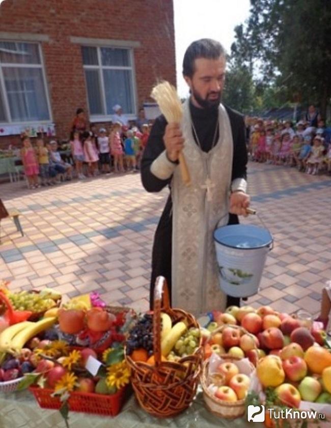 Батюшка освящает яблоки
