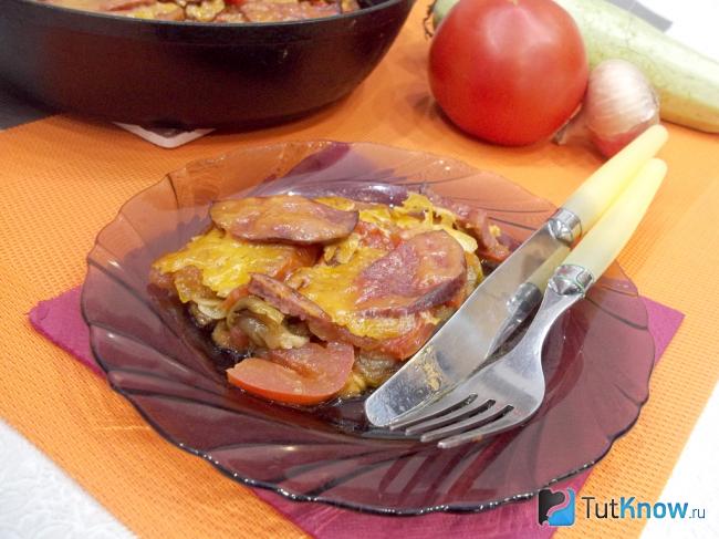 Готовые жареные кабачки с помидорами, колбасой и сыром
