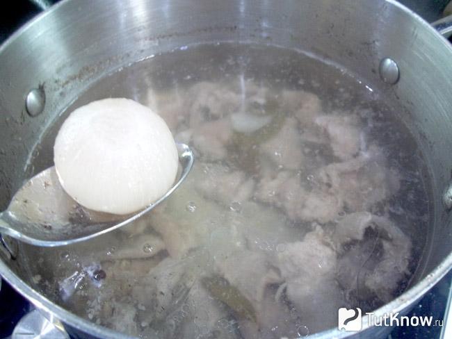 Отварная луковица извлечена из кастрюли