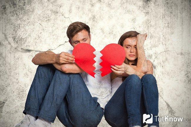 Парень и девушка держат половинки разорванного сердечка