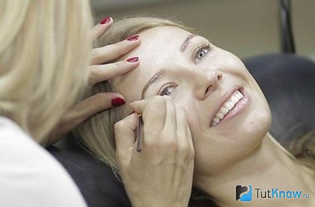 Девушке проводят осветление бровей в салоне