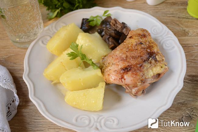 Запеченные куриные бёдра и картофель на тарелке