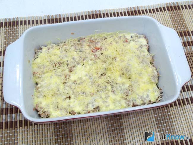 Фарш смазан сметанным соусом и присыпан сыром