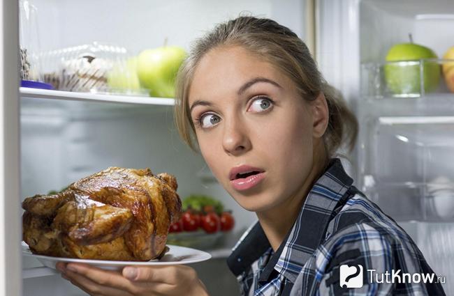 Девушка достаёт из холодильника жареное мясо
