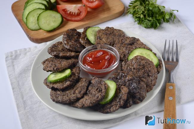 Печёночные оладьи на тарелке с кетчупом и огурчиками