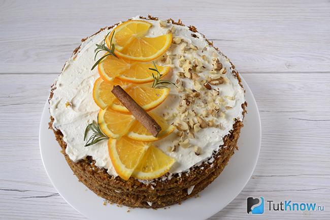 Украшение торта орехами, ломтиками апельсина, ветками розмарина и корицей