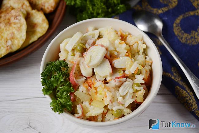 Готовый жареный рис с крабовыми палочками и горошком в тарелке