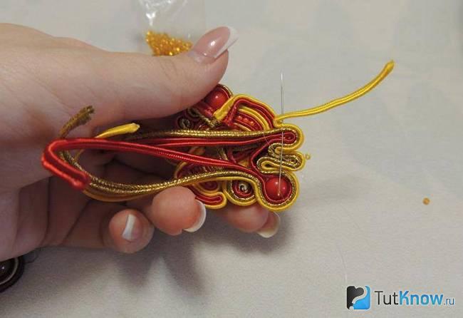 Пропускание иголки с ниткой через витки шнуров