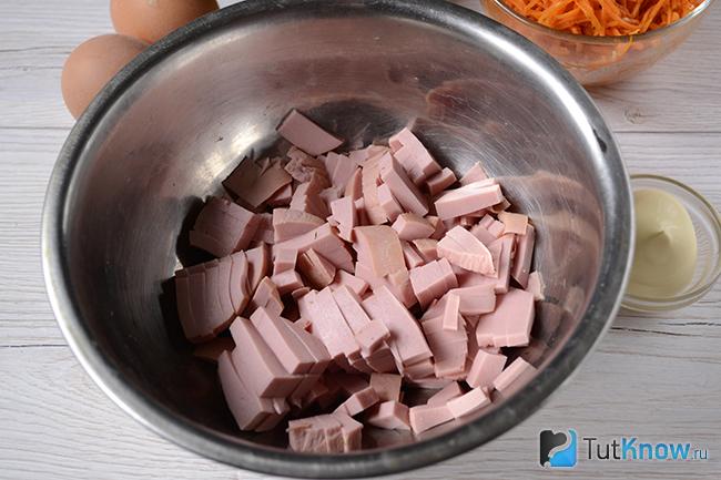 Порезанная колбаса кусочками в миске
