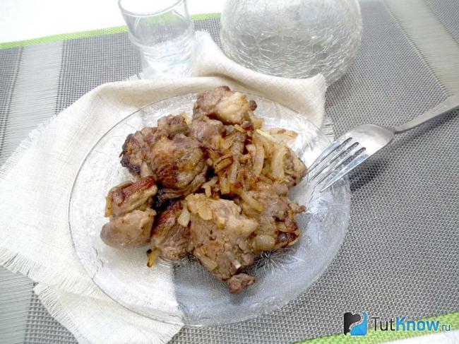 Готовая жареная свинина кусочками на сковороде с луком