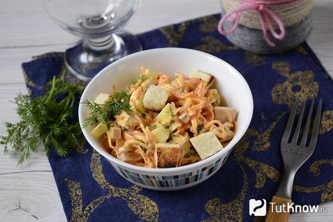 Готовый салат с корейский морковкой и колбасой с сухариками в тарелке