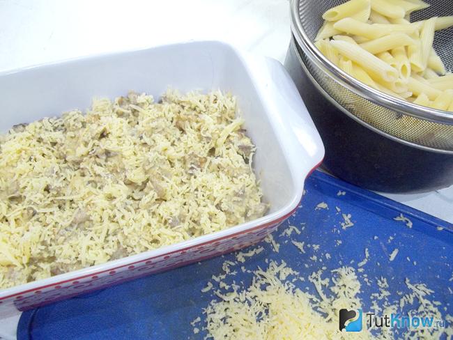 На макароны выложено мясо и присыпано сыром