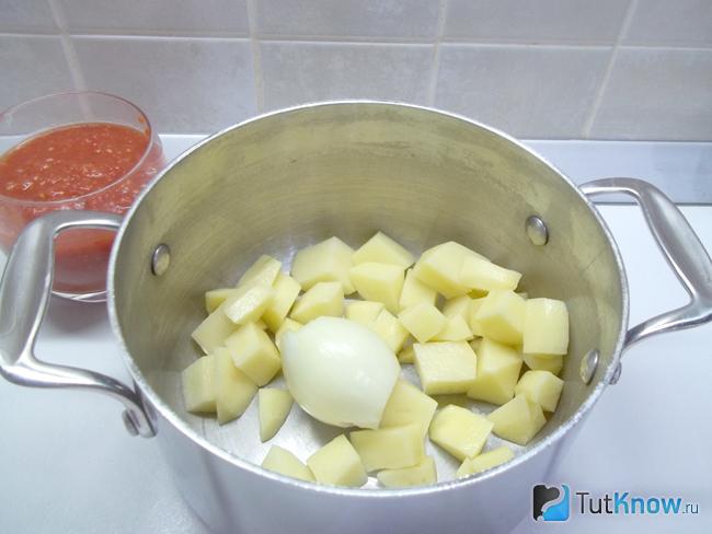 В кастрюлю сложен картофель и луковица