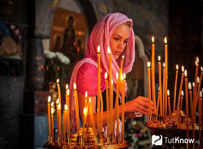 Девушка ставит свечку в церкви