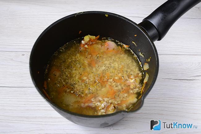 Добавление воды к перловой крупе, мясу и овощам
