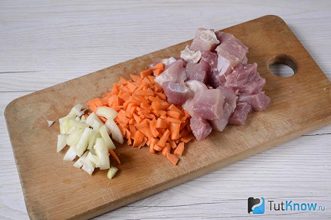 Нарезанные морковь, лук и свинина на дощечке