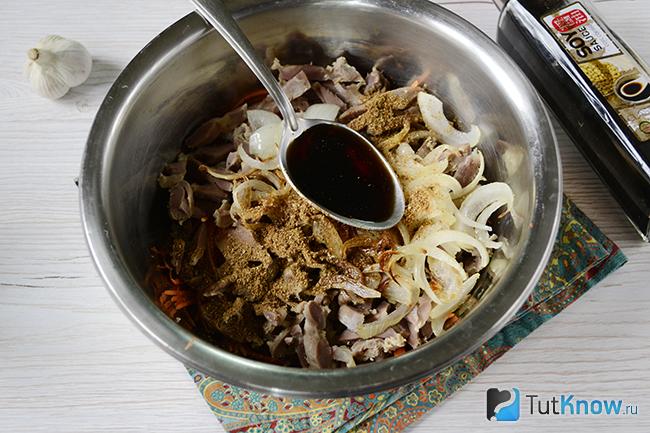 Ложка соевого соуса поверх куриных желудочков и лука