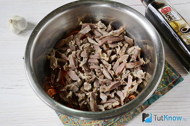 Нарезанные куриные желудки добавлены в миску с морковью