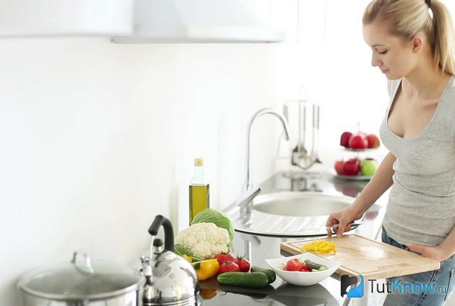 Молодая девушка занята приготовлением еды