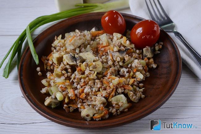 Готовая гречка с грибами и овощами в тарелке