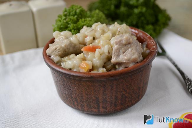 Миска с перловой кашей и мясом стоит на столе