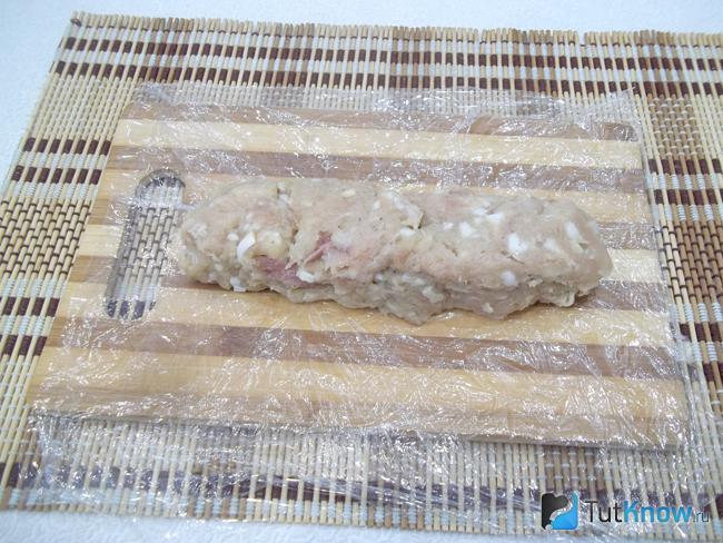 Фарш для колбасы выложен на пищевую пленку