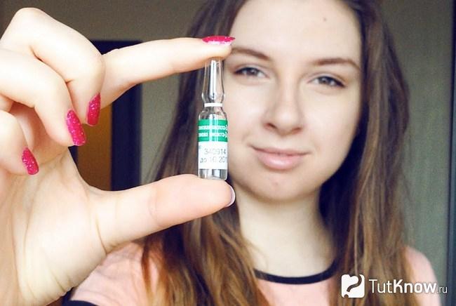 Девушка держит ампулу с никотиновой кислотой двумя пальцами