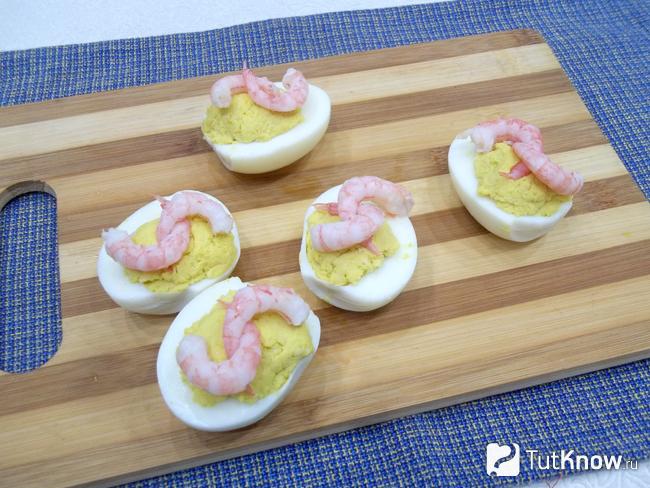 Яйца фаршированных сыром украшены креветками