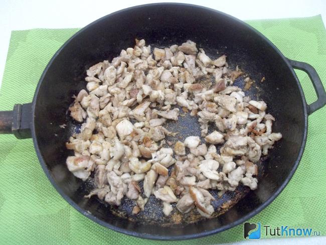 Куриное мясо жарится в сковороде в растительном масле.