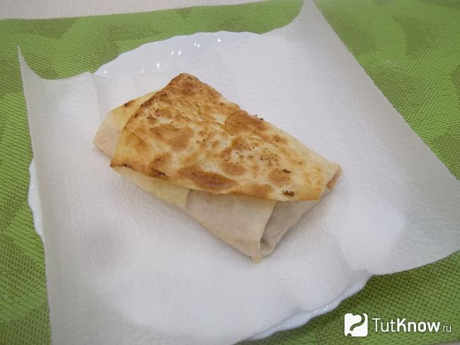 Конвертики из лаваша с курицей, сыром и корейской морковью выложены на бумажную салфетку, чтобы убрать лишний жир