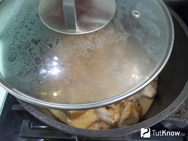 Курица тушится под крышкой на медленном огне