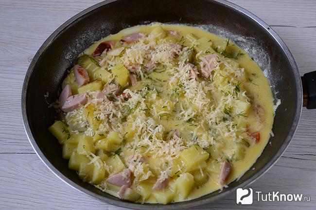 Картошка, сосиски и яйцо присыпаны зеленью и сыром