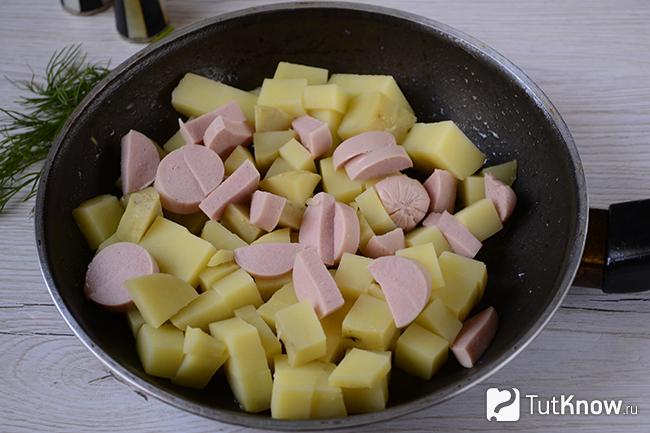 Сосиски и картошка обжариваются на сковороде