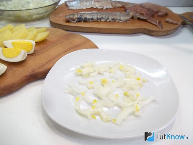 На сервировочное блюдо выложен маринованный лук
