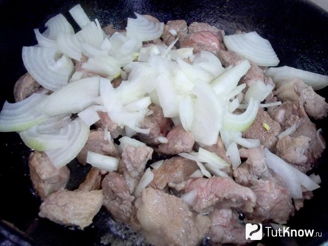 К жареному мясу добавлен нашинкованный полукольцами репчатый лук